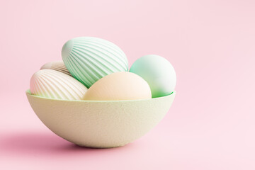 Easter decoration. Colorful eggs in bowl on pink background.