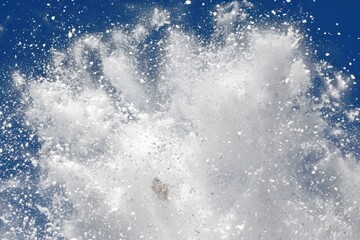 Skier jumps with snow flying from his board in mid-air.