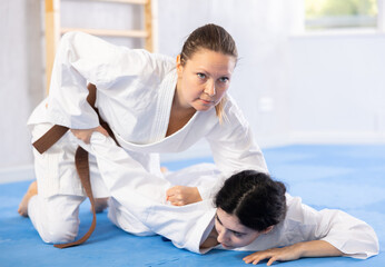 Obraz premium Young woman and adult woman practicing judo technique in gym