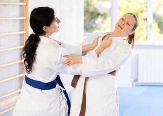 Young woman and adult woman practicing judo technique in gym