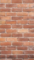 A close-up view of a textured brick wall, featuring various shades of red and orange bricks arranged in a uniform pattern.