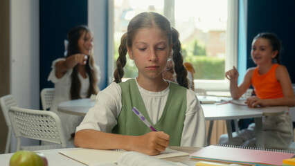Caucasian teen schoolgirl sad upset kid student pupil studying at desk class school education stress problem cruel laugh children classmates bullying mock girl child abuse bully psychological trauma