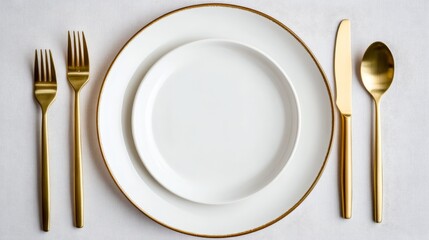 Elegant table setting featuring gold cutlery and white plates on a textured white tablecloth