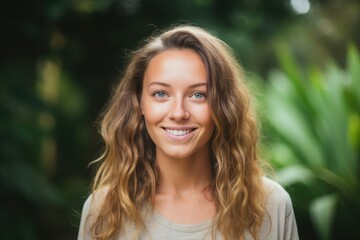 Naklejka premium With a radiant smile, a young woman stands amidst lush green foliage, capturing the serene beauty of nature. The warm light enhances her vibrant presence in this tranquil setting