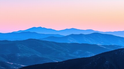 Fototapeta premium Serene sunset over layered blue mountains.