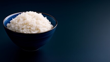 A close-up of a bowl of fluffy white rice against a dark blue background, evoking calmness