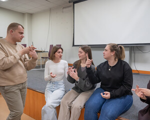 Young people communicate in sign language in a university classroom. 