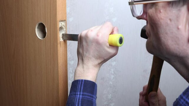 Carpenter uses chisel and hammer to carve precise mortise for latch plate, ensuring proper alignment and secure fit for door handle mechanism.
