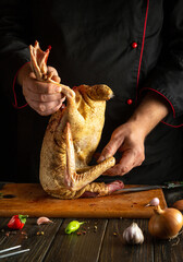 A chef skillfully handles a whole duck, preparing it for cooking on a wooden cutting board in a...
