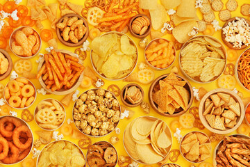 Colorful mix of salty snacks for beer varieties: chips and pretzels, onion rings and crackers. Non-healthy junk food background