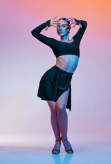 Stylish female dancer in black outfit posing in Latin dance move on vibrant gradient studio...