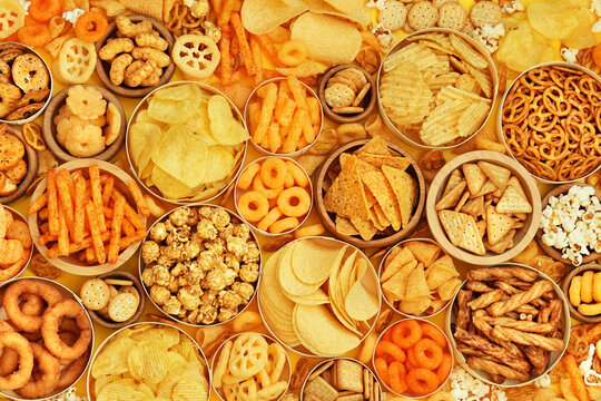 Colorful mix of salty snacks for beer varieties: chips and pretzels, onion rings and crackers. Non-healthy junk food background