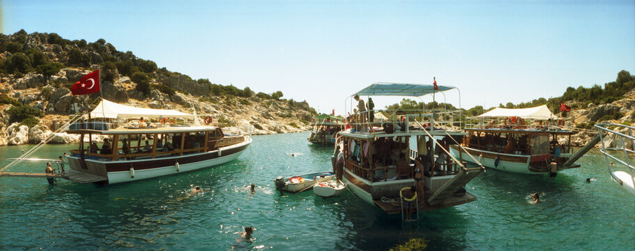 Panoramic view of boats with people swimming in the Mediterranean sea, Kas, Antalya Province, Turkey.
