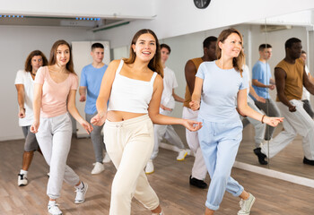 Group of energetic different people learning dance at dance class