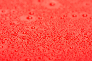 Red plastic with water drops macro photo. Abstract red background with drops.