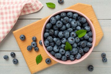 Bowl with fresh bright blueberries on wooden background,top view