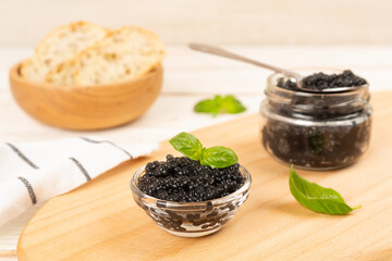 Bowl with black caviar on on wooden table