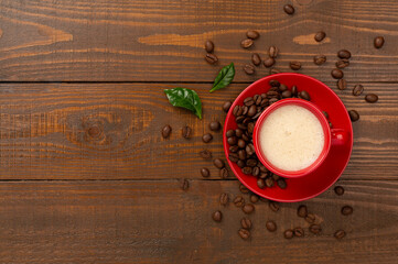 Cup of coffee with coffee beans and leaves on wooden background,top view