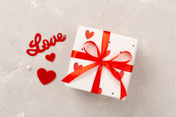 Gift boxes with red hearts on concrete background, top view