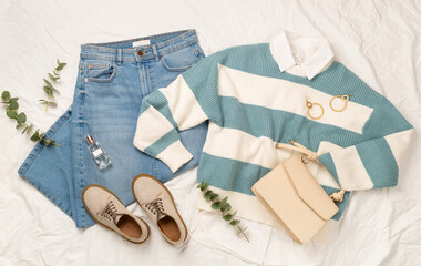 Flat lay with women's trendy spring outfit on white sheet background, top view