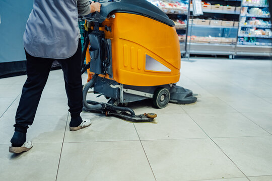 Janitor cleaning supermarket floor with a scrubber dryer machine