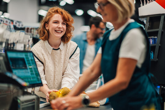 Cashier scanning groceries of a smiling customer at the supermarket checkout