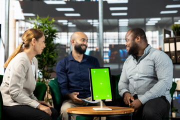 Smiling board of directors in office maintaining strong relationships with business partners, looking at metrics on isolated screen tablet. Happy manager showing shareholders data on mockup device
