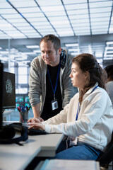 Manager checking project progress of technician programming in AI data center used for machine...
