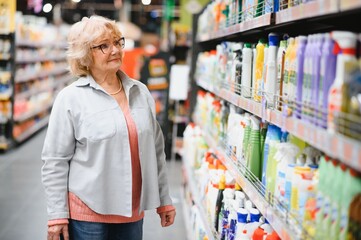 Mature female shopper buying laundry detergent in household chemicals store