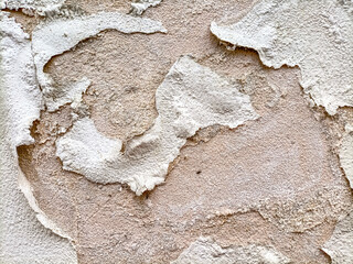  The surface of an old dilapidated wall with peeling off plaster in beige and pink shades. Abstract...