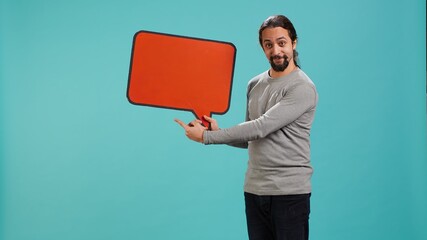 Smiling man holding red speech bubble sign of empty copy space for message. Joyous person...