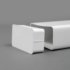 White plastic pipe with a plug on a gray background. Rectangular shape.