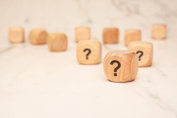 wooden blocks with question marks on a marble surface, symbolizing uncertainty and curiosity