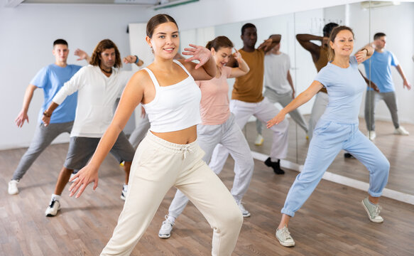 Excited sporty multiracial people practicing new movements steps during dancing training in studio