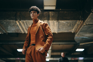 Young model in stylish brown suit posing confidently in an urban setting