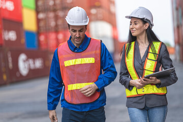 Two logistics workers man and woman discuss operations at a busy shipping container yard.