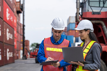 Two logistics workers man and woman discuss operations at a busy shipping container yard.