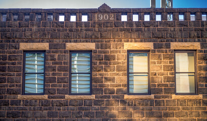 Old Brownstone Brick Building Wall with Facade and Sunlight.