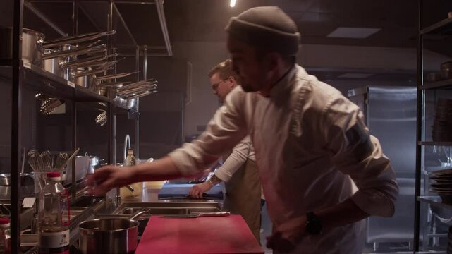 Professional men cooks taking out appliances for coking
