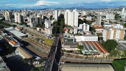 Aerial view of Belo Horizonte featuring Santa Tereza Viaduct and train station during Carnival. The cityscape blends modern and historic architecture, with busy streets and mountains in the background