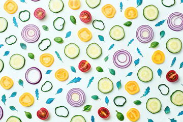 Colorful sliced vegetables and herbs arranged on white background.