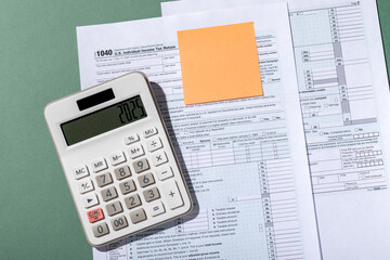 White calculator with number 2025 and empty sticker on individual income tax return form 1040