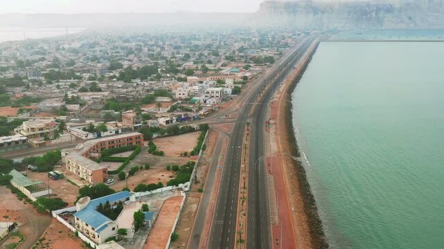 A breathtaking aerial view of Gwadar Marina Drive, a stunning coastal road in Balochistan, Pakistan, running parallel to the turquoise waters of the Arabian Sea.