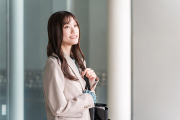 都会のオフィス街を歩く若いアジア人ビジネスウーマン
