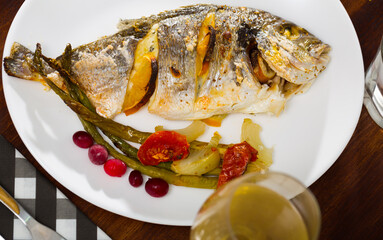 Delicious grilled gilthead bream (dorada) with lemon, baked vegetables and fresh berries..