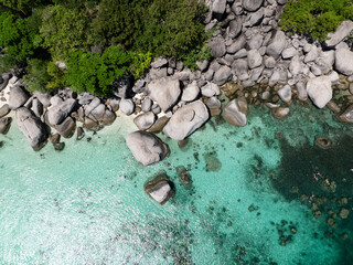 Rocky tropical coastline featuring clear waters and lush greenery under sunny skies. Nang Yuan, Koh...