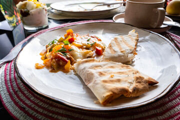 A hearty breakfast in a restaurant, shawarma and scrambled eggs with vegetables on a plate.