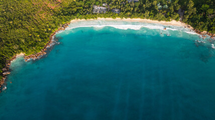 A pristine turquoise bay with a secluded sandy beach, bordered by lush green hills and tranquil waters. Anse Lazio, Seychelles.