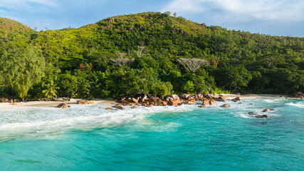A beautiful, untouched beach meets the foot of a vibrant green hillside. Anse Lazio, Seychelles.