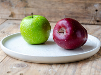 green and red apples on  white plate on the kitchen table